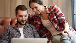 young couple sitting on sofa and using laptop Stock Footage