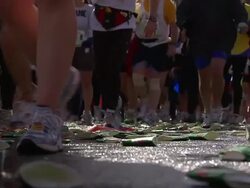 Athletes walk and run over discarded cups during a marathon. Stock Footage