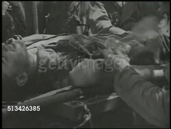 1944: BATTLE OF SAIPAN:  VS U.S. medics tending to 2nd &amp; 4th Marine Division &amp; 27th Infantry Regiment soldiers, SEMI-GRAPHIC medic bandaging arm w/ open wound, soldiers kneeling over deceased body (KIA, Killed in Action), FADE TO BLACK. WWII Instructional Video