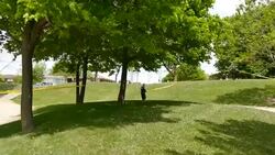 Police officer unrolling crime tape on sunny grassy hill Stock Footage