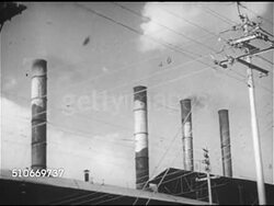 1953: PROGRESS REPORT ON PAKISTAN: TU WS Factory smokestacks behind telephone wires, WS Hot molten metal being poured into smelting pot, MS Hands pouring molten metal from smelting pots into molds standing between bricks. Instructional Video