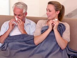 Sick couple sitting on the couch under a blanket Stock Footage
