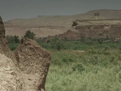 The heat of the day shimmers against the backdrop of rustic buildings and North African vegetation. Stock Footage