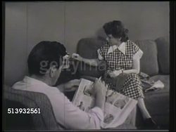 1951: MAIL ORDER: VS Male & female, couple, sitting in living room, male reading mail order catalog, female sewing. MCU Male hands flipping through catalog, clothing section, overalls. Instructional Video