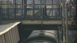 Commuters cross a sky bridge over a slow-moving train in India. Stock Footage