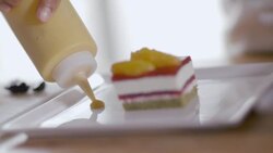 Pastry chef decorates dessert dish with yellow sauce from squeeze bottle Stock Footage