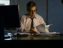 Medium shot. Pan up desk to man at hs desk working late. The camera dollies to the right around the desk Stock Footage