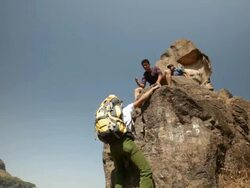 Young man climbing rock with his friend helping him  Stock Footage