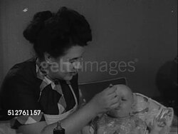 1953: BABY'S EARLY MONTHS: Brunette mother feeding baby w/ spoon, hardly giving time to swallow, baby making faces.  [SOT Dr. Spock saying shouldn't make them eat what they don't want, argue about food, easy to argue on other things]... Instructional Video