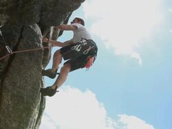 Boom upward to teenager leading rock climb, clipping protection Stock Footage