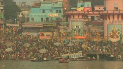 Colorful murals of Hindu gods overlook hundreds waiting to bathe in the Ganges. Stock Footage