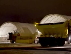 A plow passes in front of a few shelters that contains salt and calcium Stock Footage