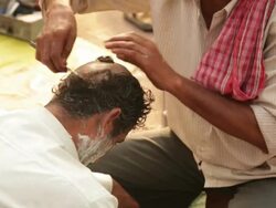Barber shaving head of a man, Haridwar, Uttarakhand, India Stock Footage