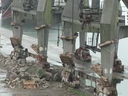 MS CU Legs of large steel crane, rigged with explosives, explode in controlled demolition / Liverpool, NorthWest England, UK Stock Footage