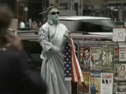 Person posing as the Statue of Liberty attempts to sit down while selling his wares. Stock Footage