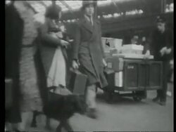 Passengers and porters on station platform; cars parked next to platform, United Kingdom, 1939 Stock Footage