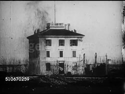 1917: WWI AVIATION: TU WS Biplane in flight, WING MS Biplane cockpit w/ copilot lifting up bomb, WS Bomb exploding in front of three story building. XWS Open field w/ soldiers running, WS Soldiers around downed biplane, soldier sitting (implied pilot). Instructional Video