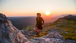 Female athlete running on rocky terrain in mountains at sunset Stock Footage