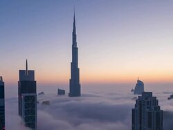 Time Lapse of Burj Khalifa rising above fog at dawn, night to day, zoom out Stock Footage