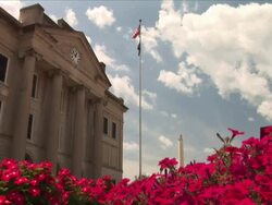 Low Angle pan-left - Red flowering bushes grow in front of the St. Clair County Courthouse in Belleville, Illinois. / Belleville, Illinois, USA Stock Footage
