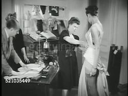 MOT 1947: PARIS, FRANCE: FRENCH FASHION: *WS Sign 'Rond Point des Champs Elysees' & 'Christian Dior' signs, Designer Christian Dior (1905-1957) in front of desk adjusting fabric on model, VS Models modeling Dior's first collection ('New Look') Instructional Video