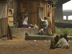MS Shot of people playing football in shanty village under road bridge / Lagos, Nigeria Stock Footage