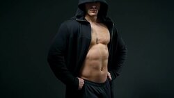 handsome young man with good muscles in a cape over a black background Stock Footage