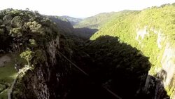 Man traverses highline stretched above waterfall, valley Stock Footage