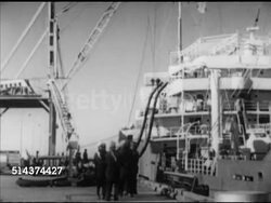 1952: KUWAIT: SHIPPING: VS Oil tankers docked in Gulf of Azadi port, HA WS Oil transfer pipelines along docks, VS Workers lowering on-shore terminal hose, attaching to ship's tank using hand-held wrench to tighten.    Crude, non-sustainable fossil fuel. Instructional Video