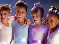 Close up four young ballerinas in tutus standing w/arms around each other and smiling at CAM Stock Footage