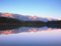 Mountains at sunset reflecting their glow in Alpine Lake Stock Footage