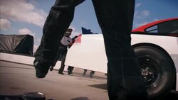 Pit-crewman rolls jack out from under race-car, driver speeds off, pit-crew celebrates Stock Footage