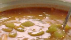 pot of clear vegetable soup as ladle scoops out a portion with chunks of celery Stock Footage