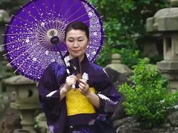 MS Shot of Mature woman in traditional Japanese clothing calling Yukata with fan and umbrella / Tokyo, Japan Stock Footage
