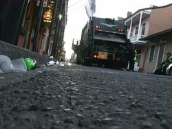 Medium Shot Low Angle - Men dumping trash into garbage truck / New Orleans Louisiana Stock Footage