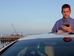 MS Man typing on mobile phone while standing in sunroof opening of car / Portland, ME, United States Stock Footage