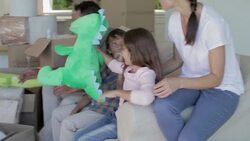 Family unpacking stuffed animals from moving boxes in living room Stock Footage