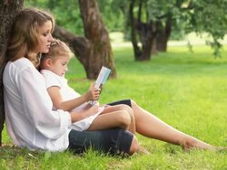 Mother and daughter reading book in park Stock Footage