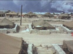 Amateur Vietnam Marine Footage panning across camp, barracks and tents with dark smoke and bright skies. 'Troy N.Y. 13,000.' Stock Footage