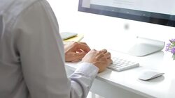 Businessman hands typing on keyboard with office equipment and desktop computer Stock Footage