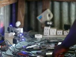 Numerous power sockets and phones charging on a table top, with hands holding  one phone Stock Footage