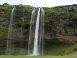 WS View of waterfall crashing into small body of water / Vestmannaeyjar, Sudhurland, Iceland Stock Footage