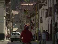 "View of street bordering Plaza De La Armas, changing to uphill, national flag of Peru and traffic lights, busy pavement, Chachapoyas, Peru [PerÃƒÂº]" Stock Footage