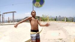 Young Brazilian boy juggles soccer ball in slow motion over Rio slum Stock Footage