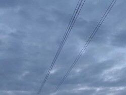 Tilt from high tension power lines to electrical power plant with three smokestacks alongside river at dusk Stock Footage