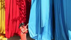 A woman in a sari checks the quality of freshly dyed fabric hanging to dry at a sari garment factory in Rajasthan, India. Stock Footage