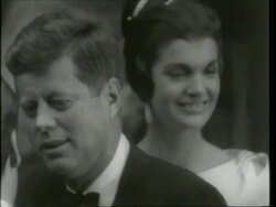 May 6, 1961 FILM MONTAGE MS John F. Kennedy, Jacqueline Kennedy, and Dean Rusk exiting building in formalwear/ CU John F. and Jacqueline Kennedy/ MS Kennedys getting into car/ WS Crowd waving as car drives off/ London, England/ AUDIO Stock Footage