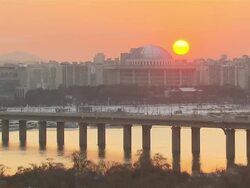 WS T/L View of Han River near National Assembly and traffic moving on bridge in Yeouido at Sunset / Seoul, Seoul, South Korea Stock Footage
