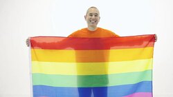 Mature adult holding gay pride flag against white backdrop Stock Footage