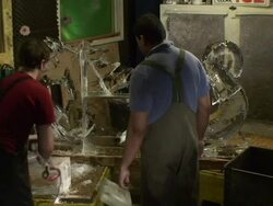 An artist uses a small chainsaw to slice through a block of ice as part of a dragon-horse ice sculpture. Stock Footage